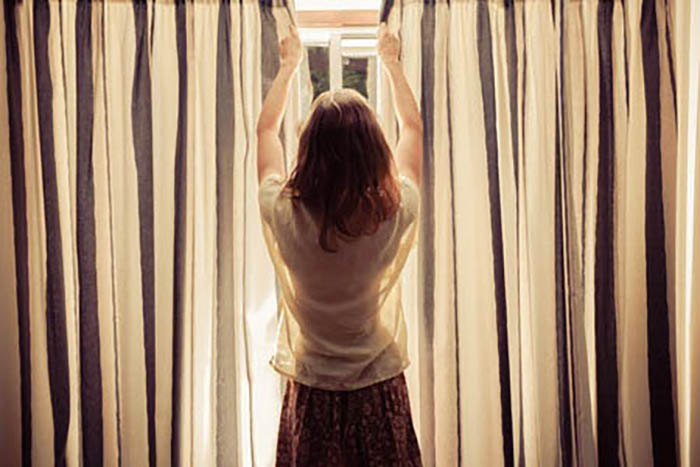 Woman closing curtains on a window
