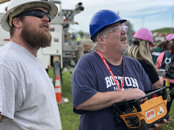 Teacher operates the controls of an auger utility truck as a lineman watches.