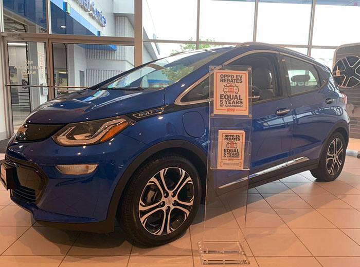 Signage explaining OPPD's EV rebate program sit alongside a Chevy Bolt at a local Omaha dealership.