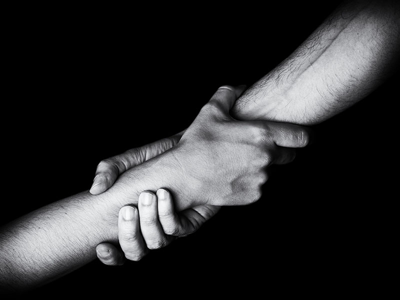 CARES assistance, utility assistance, Man saving, rescuing and helping woman by holding or griping the forearm. Male hand and arm pulling up female. Concept of rescue, love, friendship, support, teamwork, partnership, reaching, couple